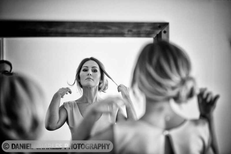 black and white wedding preparation photo of a bridesmaid adjusting her hair in a mirror