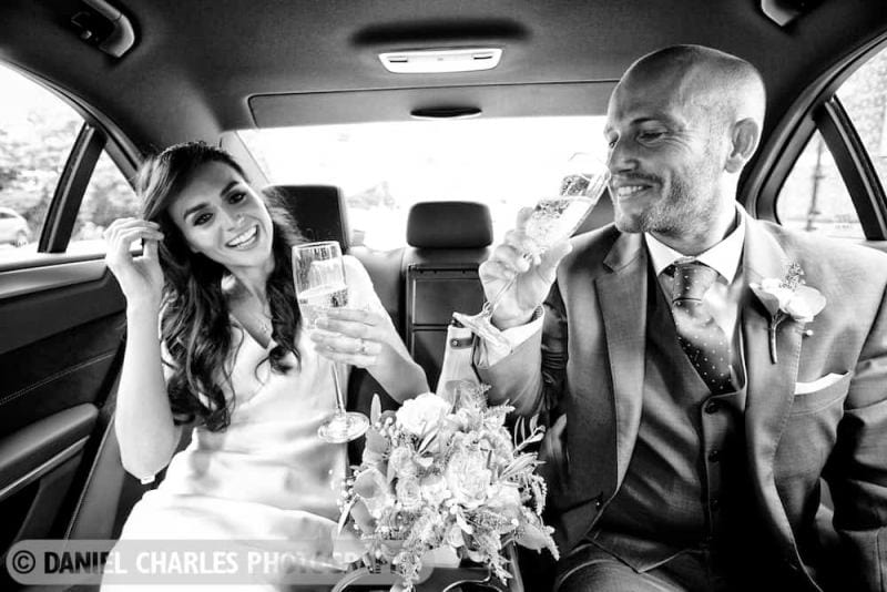 bride and groom sipping champagne in wedding car black and white wedding photography in liverpool