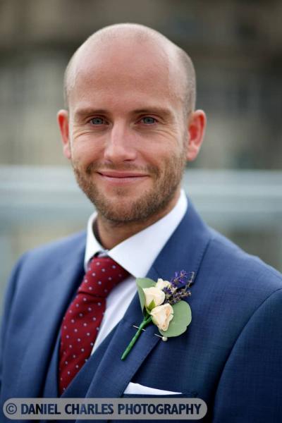 head and shoulders portrait of groom smiling to camera