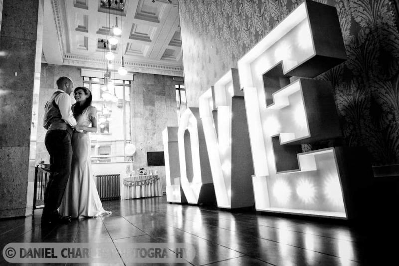 black and white wedding photograph of illuminated love sign in oh me oh my liverpool