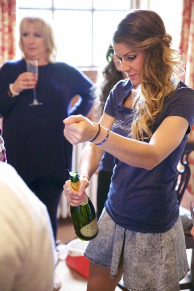 bridesmaid popping cork of champagne