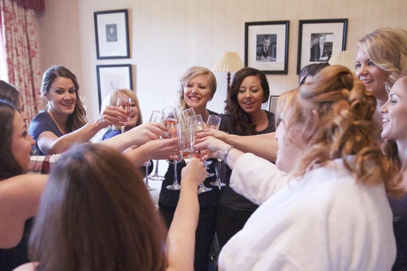 bride and bridesmaids clinking champagne glasses