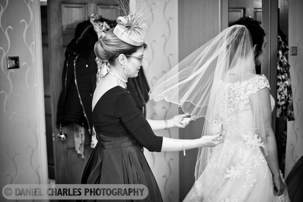 black and white wedding photo of bride having veil adjusted