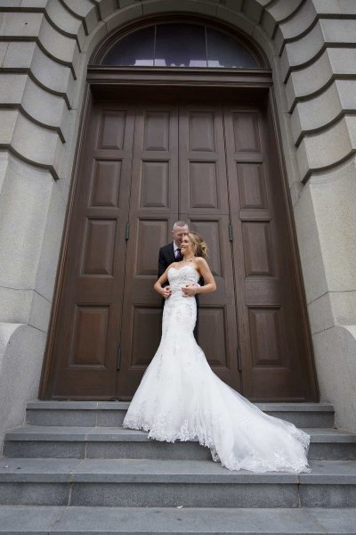 bride and groom standing on steps outside huge door in liverpool