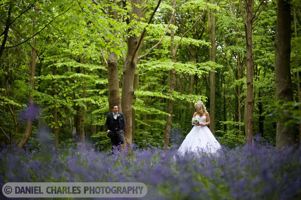 Bride looks at groom in bluebell woodland